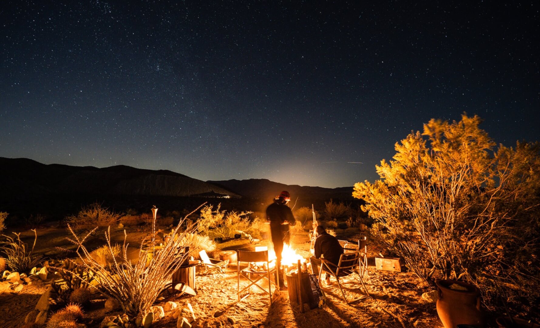 A shot of a group of campers out in nature, enjoying their cannabis wellness products from Xzibit's West Coast Cannabis, around the campfire.